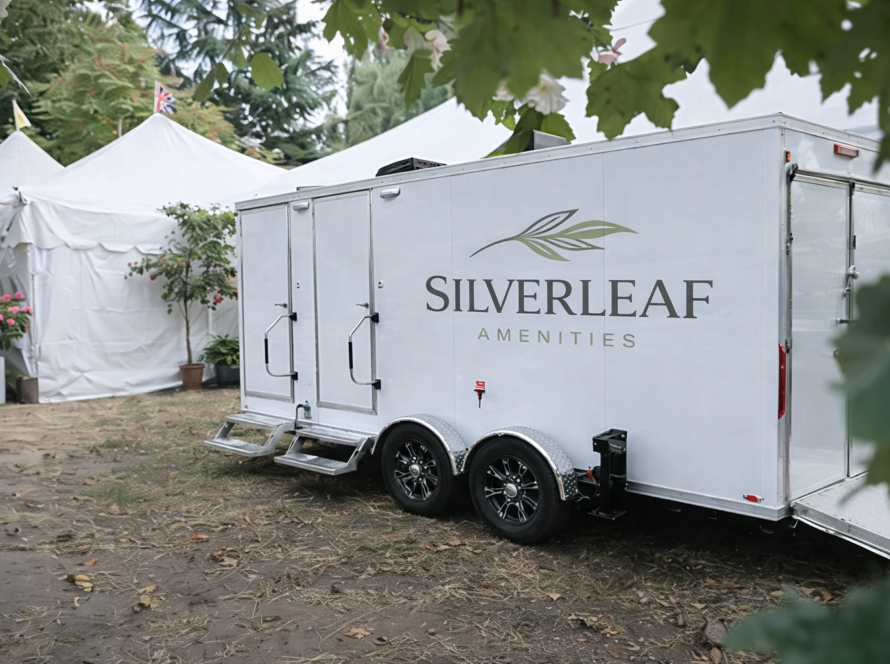 Luxury restroom trailer positioned beside large white event tents at an outdoor gathering or festival.