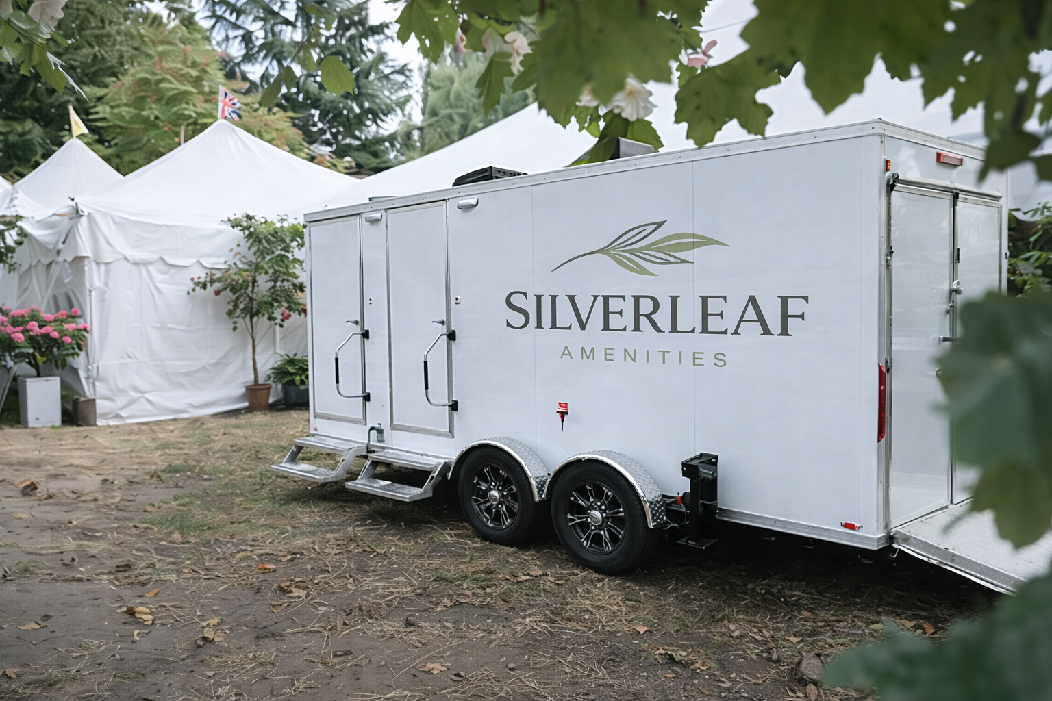 Luxury restroom trailer positioned beside large white event tents at an outdoor gathering or festival.