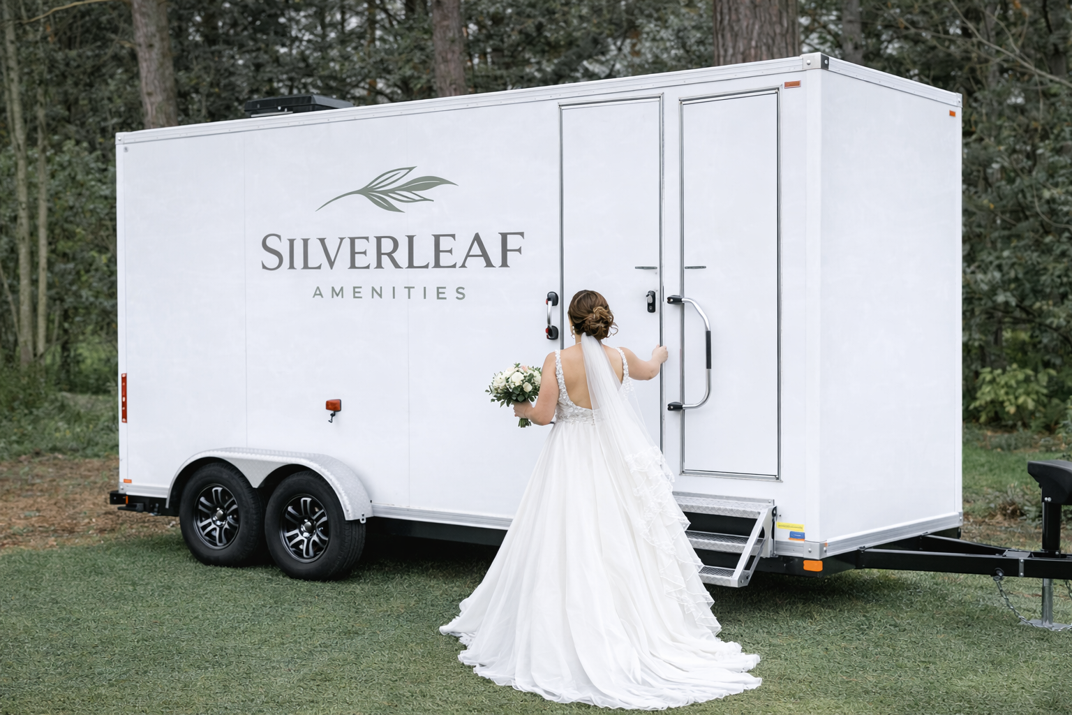 Bride in wedding gown entering a luxury restroom trailer with separate men and women entrances at an outdoor garden event.