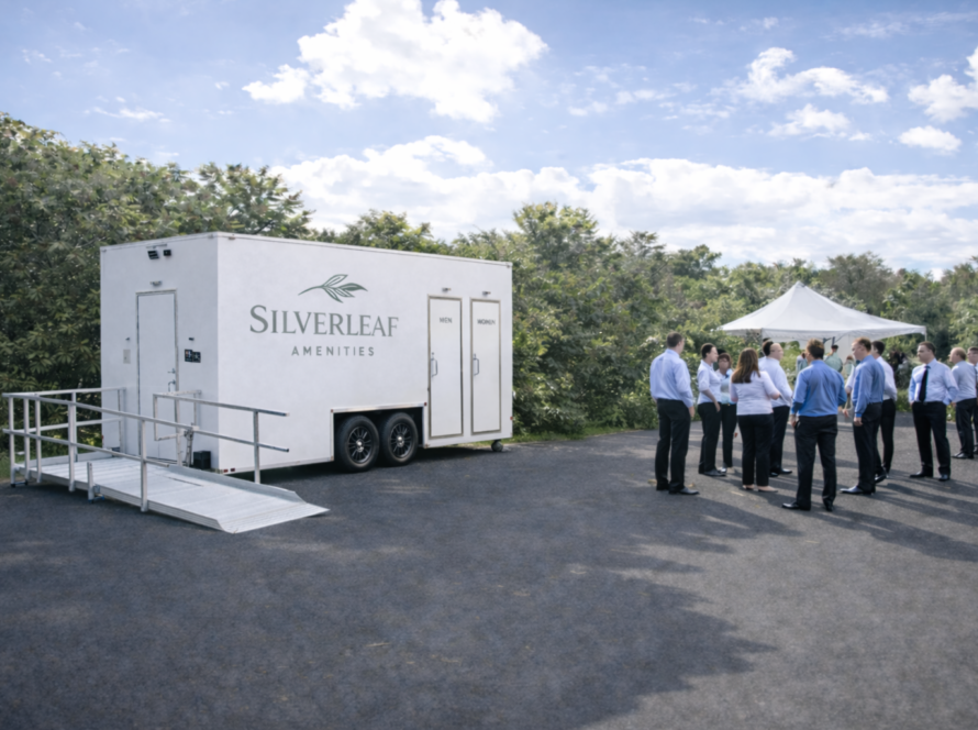 Business professionals near mobile restroom trailer