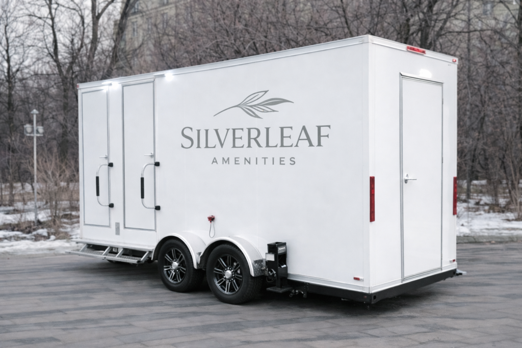 White luxury restroom trailer with steps and Silverleaf Amenities logo parked outdoors on paved ground in winter setting