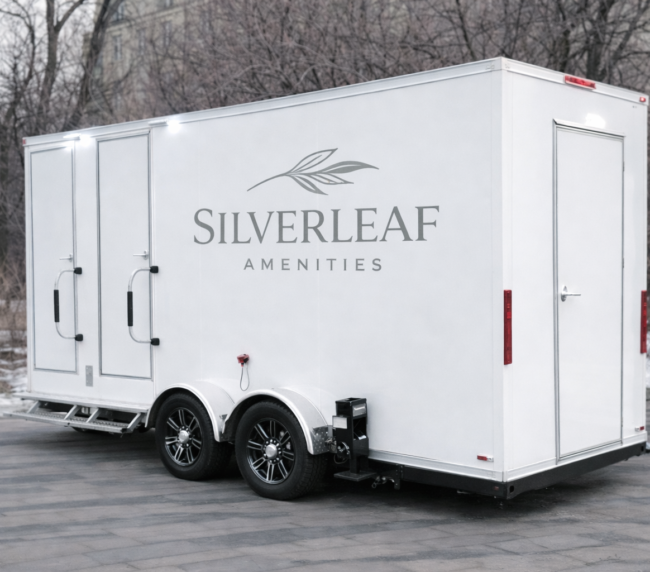 White luxury restroom trailer with steps and Silverleaf Amenities logo parked outdoors on paved ground in winter setting