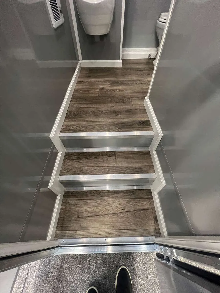 Interior view of restroom trailer steps with non-slip flooring leading to restroom area, designed for safe use at Colorado events and job sites