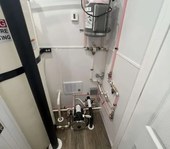 Mechanical room inside restroom trailer showing water heater and plumbing system, ensuring reliable operation for rentals in Colorado