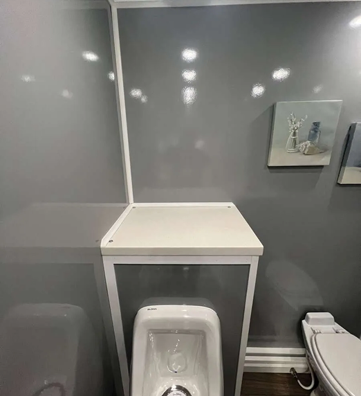 Clean modern interior of a luxury restroom trailer with urinal and toilet, available for event and construction rentals in Colorado
