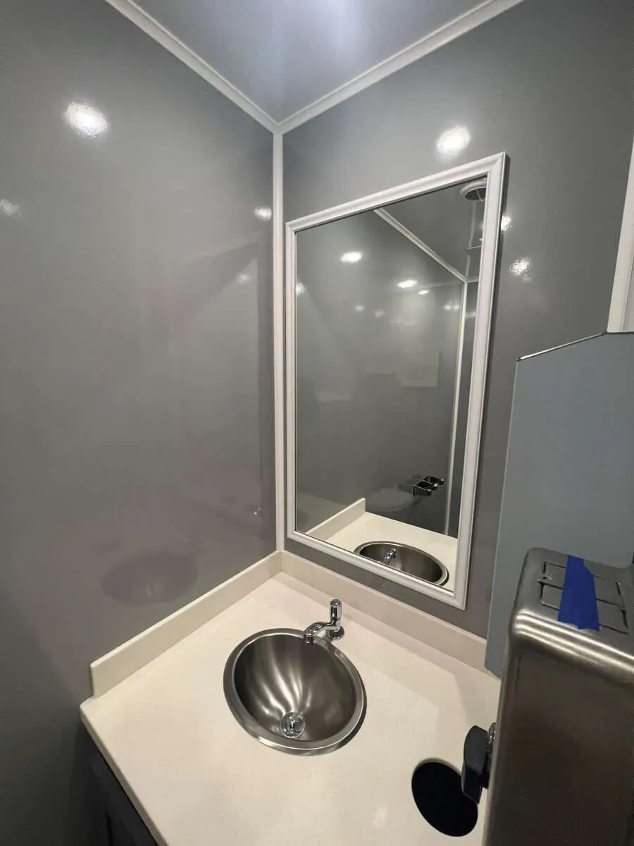 Modern sink and vanity inside a luxury restroom trailer with mirror and countertop, available for event and construction rentals in Colorado