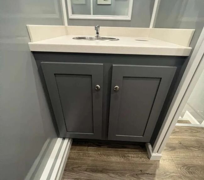 Modern vanity cabinet with sink inside a luxury restroom trailer, featuring premium interior finishes for event and construction rentals in Colorado