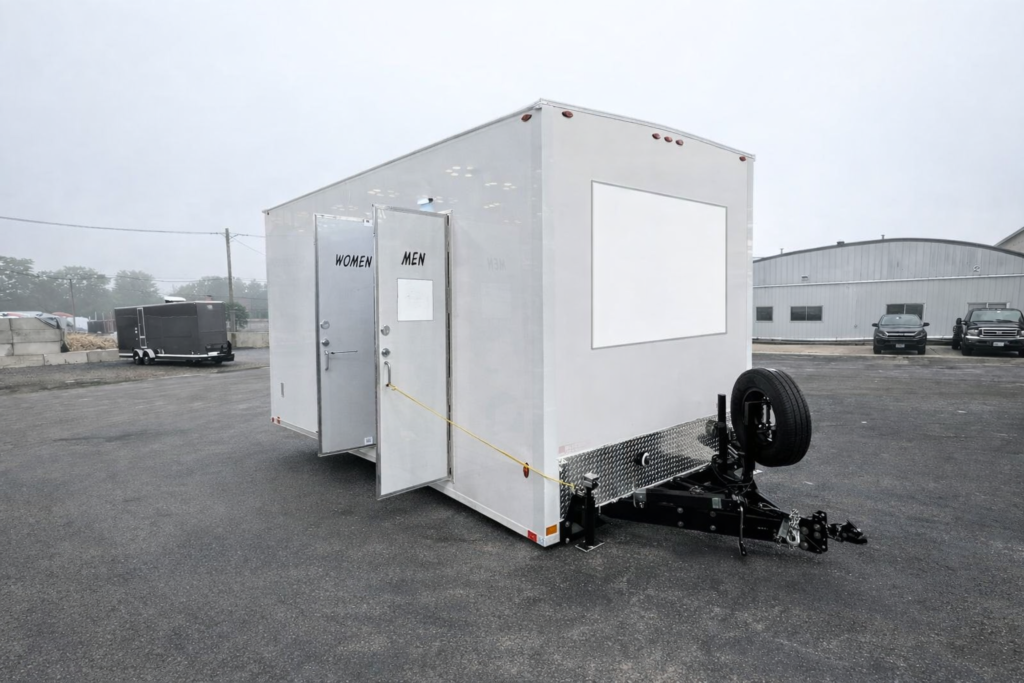 Portable restroom trailer with separate men and women entrances displayed indoors, available for event and construction rentals in Colorado