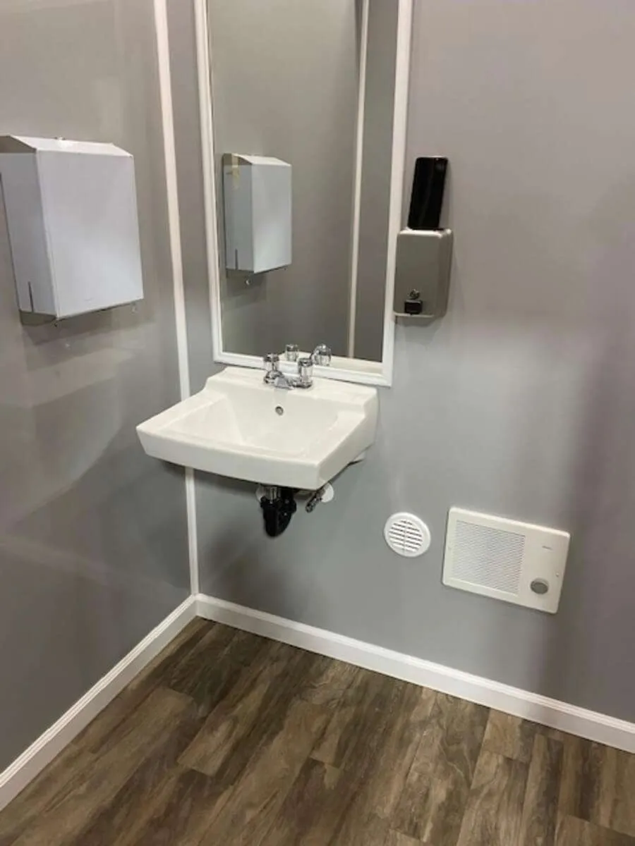Wall-mounted sink with mirror inside a portable restroom trailer, ideal for event and construction rentals in Colorado