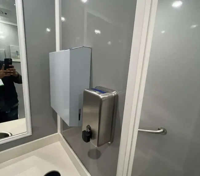 Interior of restroom trailer with paper towel dispenser and handrail, offering clean and convenient facilities for Colorado rentals