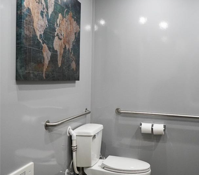 Clean and modern interior of a luxury mobile restroom trailer featuring toilet, grab bars, and elegant decor for event guests.